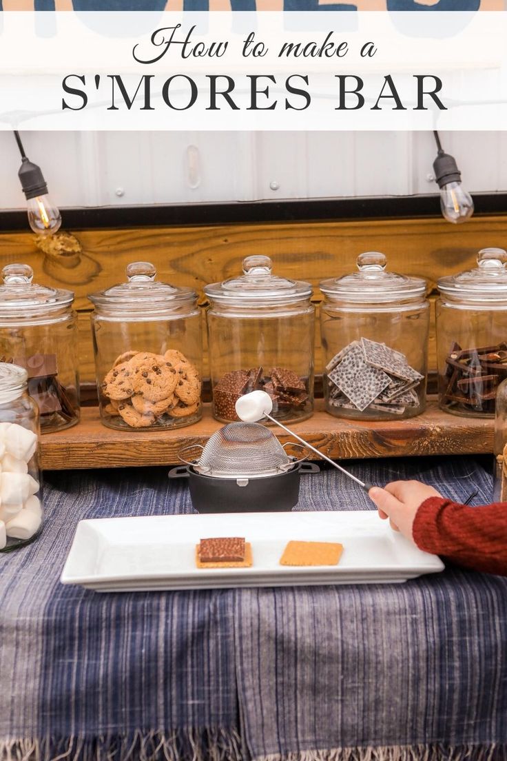 a person sitting at a table in front of jars with cookies and marshmallows