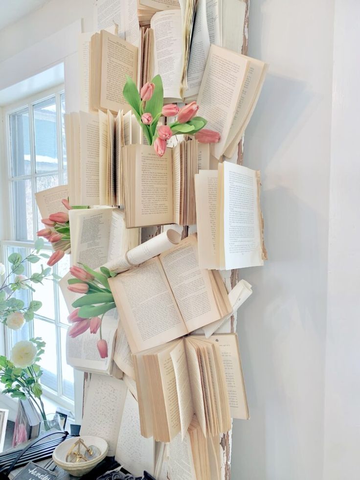 an arrangement of books hanging on the wall with tulips and flowers in them