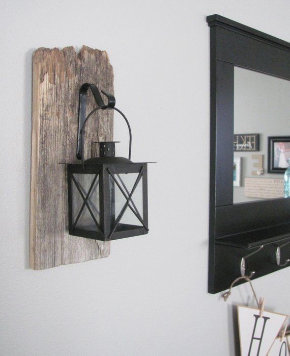 a lantern is hanging on the wall next to a mirror and wooden planks are hung on the wall