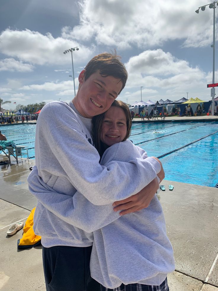 a man and woman hugging in front of a swimming pool