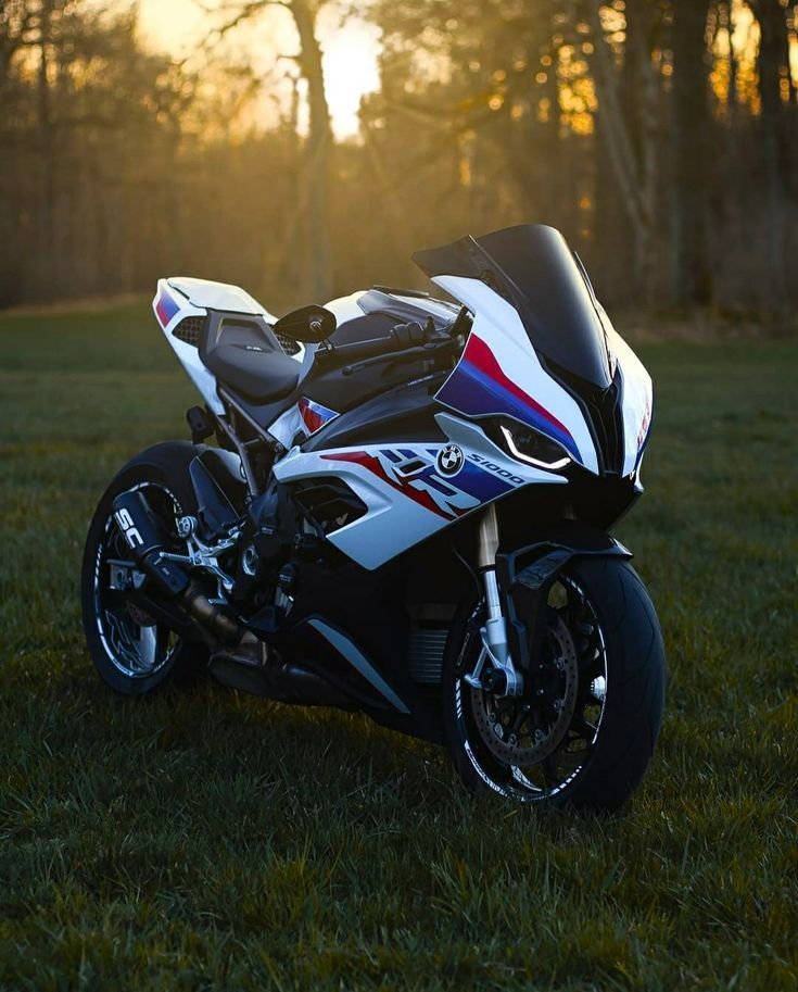 the motorcycle is parked on the grass in the sundown area with trees in the background