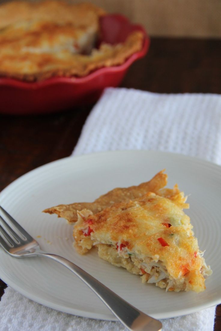 a slice of quiche on a white plate with a fork next to the pie