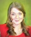 a blurry photo of a woman in a red shirt smiling at the camera with green wall behind her