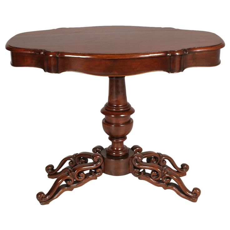 a round wooden table with ornate carvings on the legs and top, against a white background