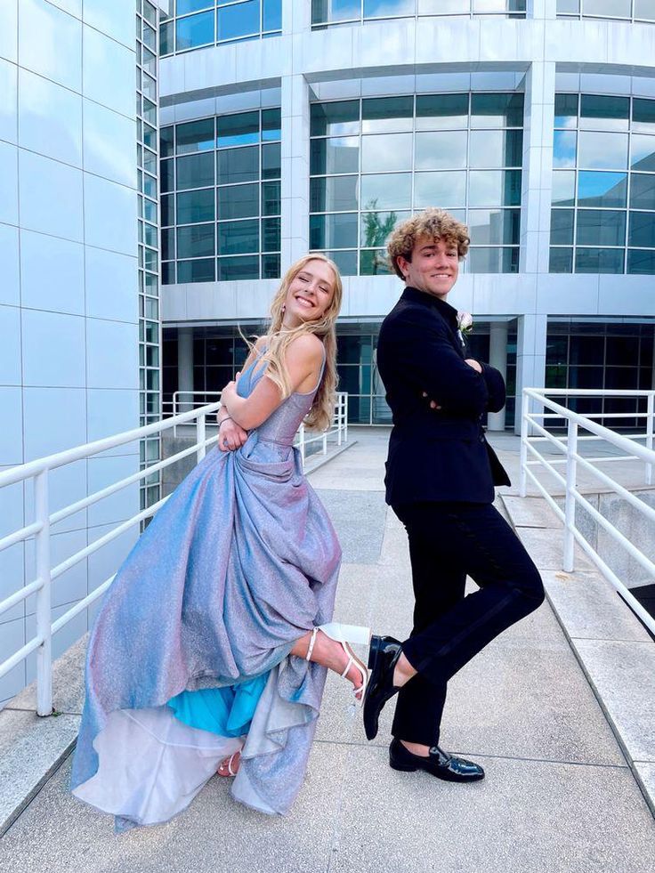 two people posing for a photo in front of a building