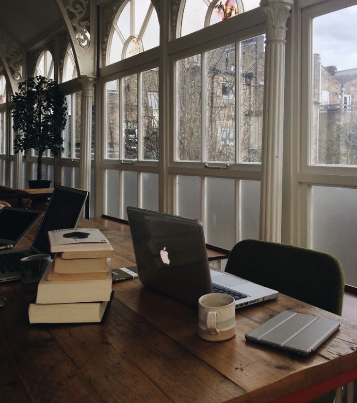 an open laptop computer sitting on top of a wooden table next to a cup of coffee