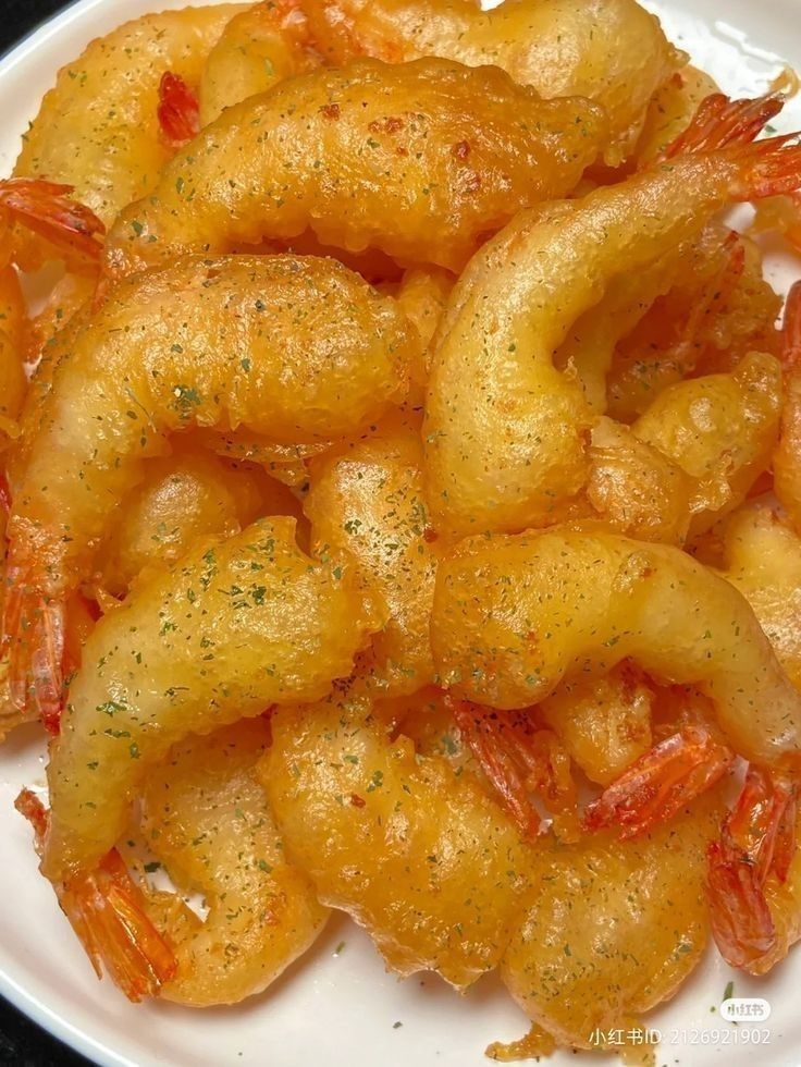 some fried shrimp on a white plate with seasoning