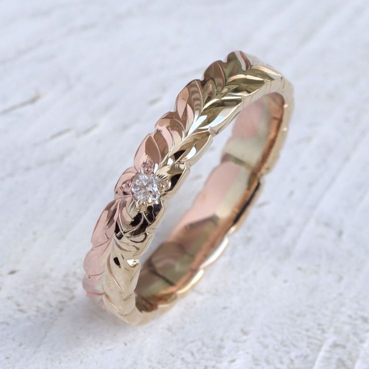 a gold wedding ring with leaves and a diamond