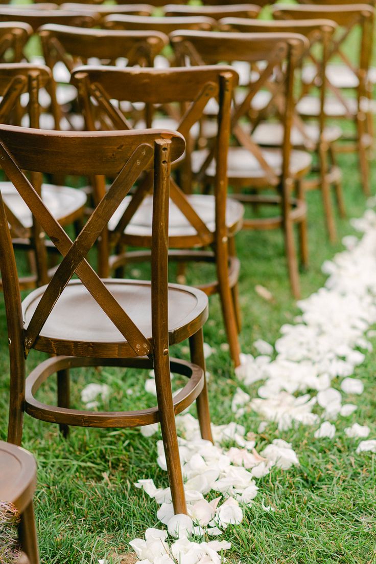 rows of wooden chairs with white flowers on the grass