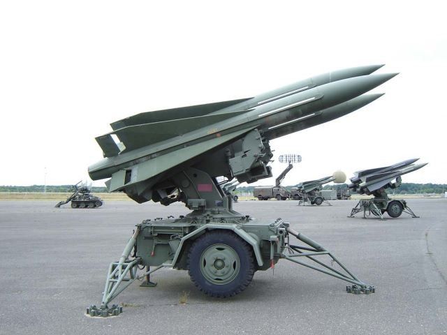 an army vehicle with missiles on it's flatbedd area in front of other planes