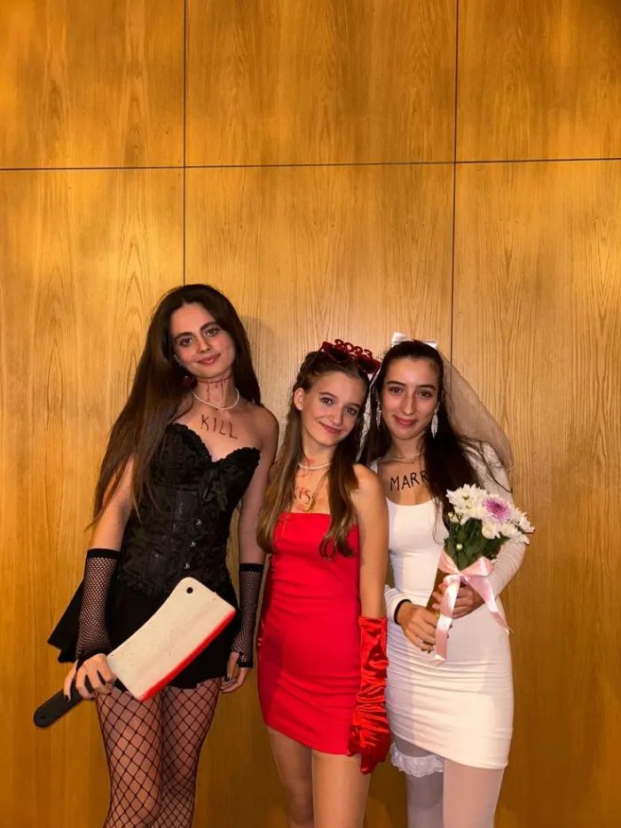 three young women dressed up in costume posing for a photo with one holding a bouquet