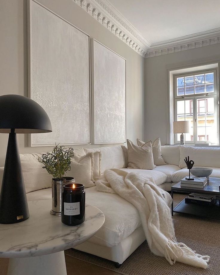 a living room filled with furniture and a lamp on top of a coffee table in front of a window