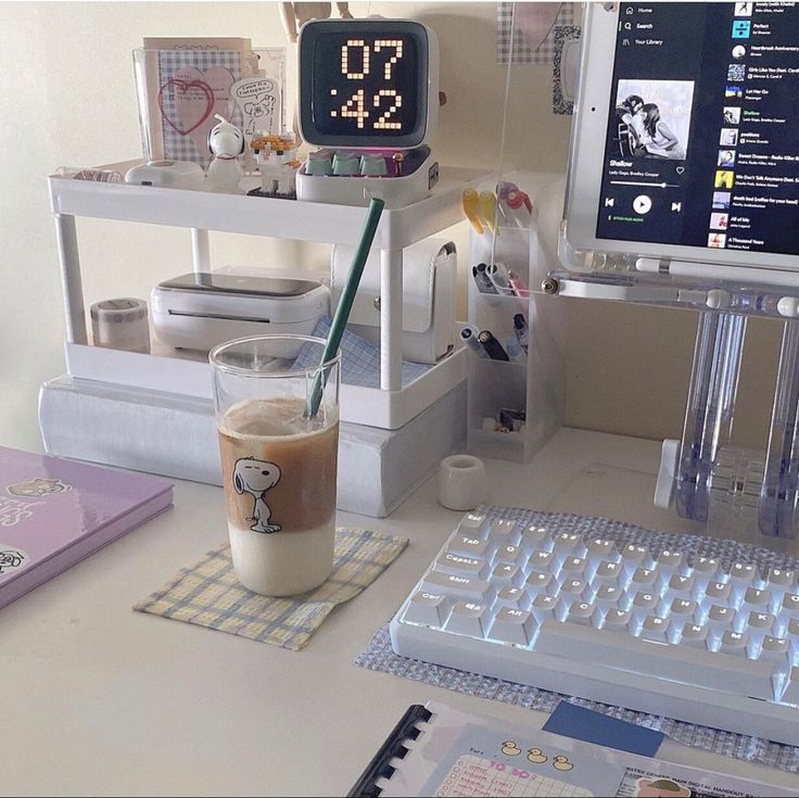 a cup of coffee sitting on top of a desk next to a keyboard and monitor