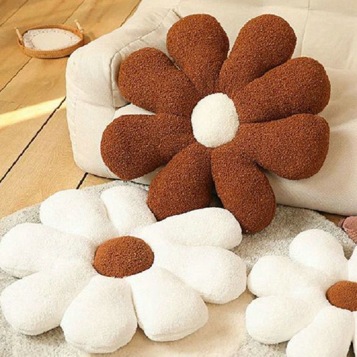 three flower shaped pillows sitting on the floor next to a white bag and some other items