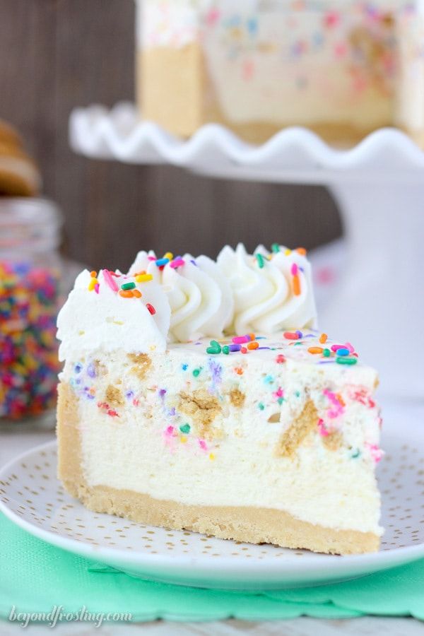 a slice of cake with white frosting and sprinkles on a plate