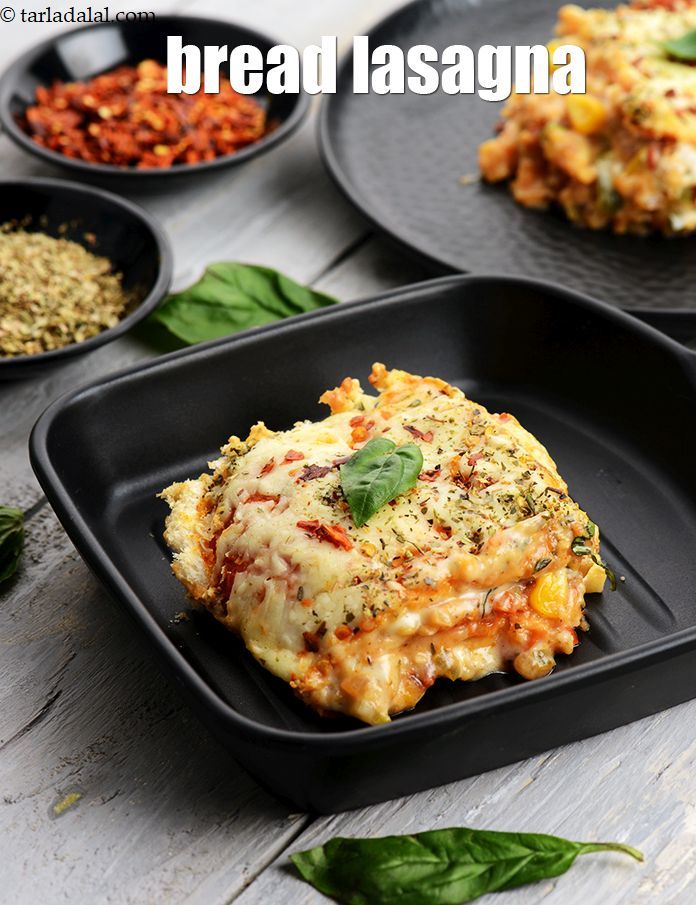 three black plates topped with lasagna covered in cheese and sauce next to spinach leaves