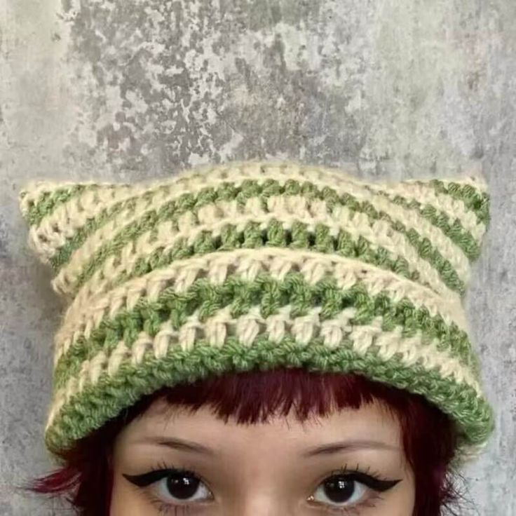 a woman with red hair wearing a green and white crocheted hat on top of her head