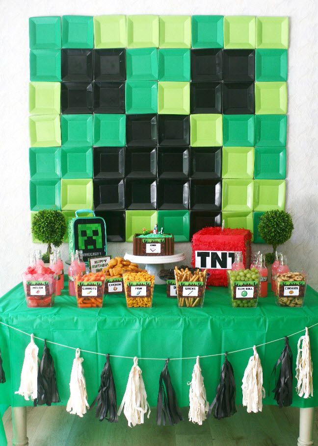 a green table topped with lots of food and desserts next to a wall made out of blocks