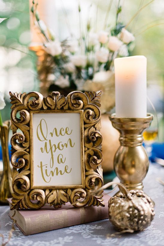 a gold frame sitting on top of a table next to a candle