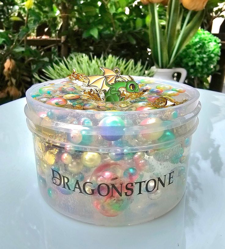 a container filled with lots of colorful beads on top of a table next to flowers