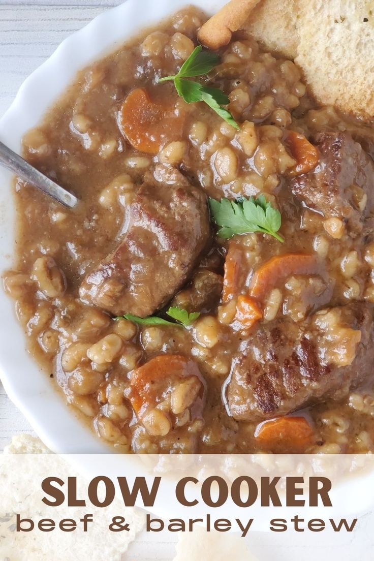 slow cooker beef and barley stew in a white bowl with bread on the side