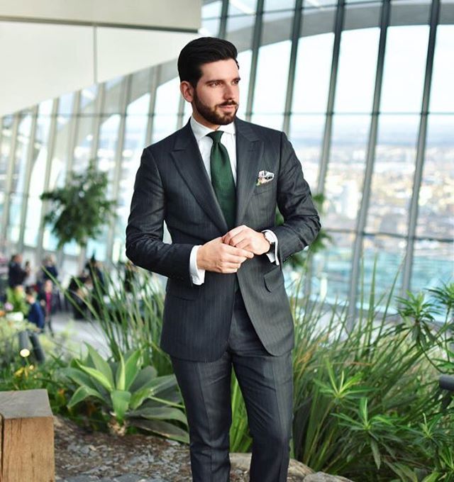 a man in a suit and tie standing by some plants