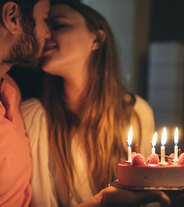 a man and woman kissing in front of a cake with lit candles on the top