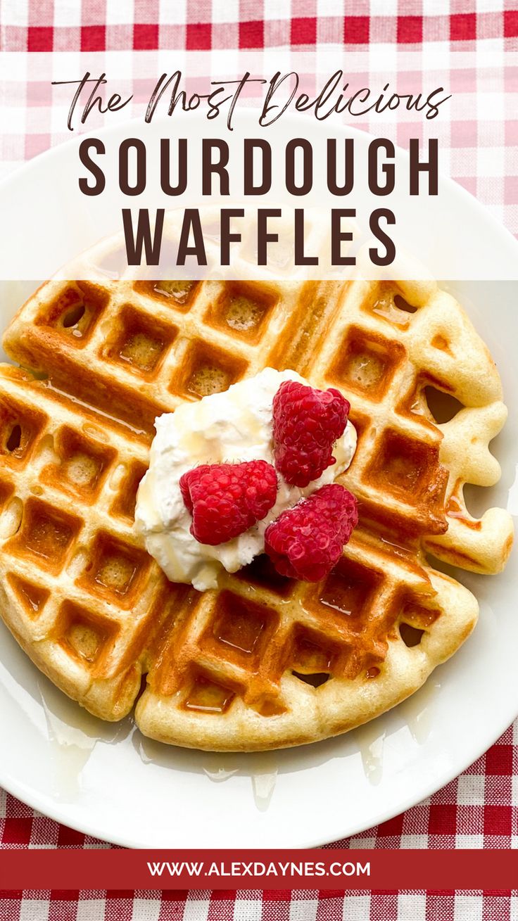 a white plate topped with waffles covered in whipped cream and raspberries