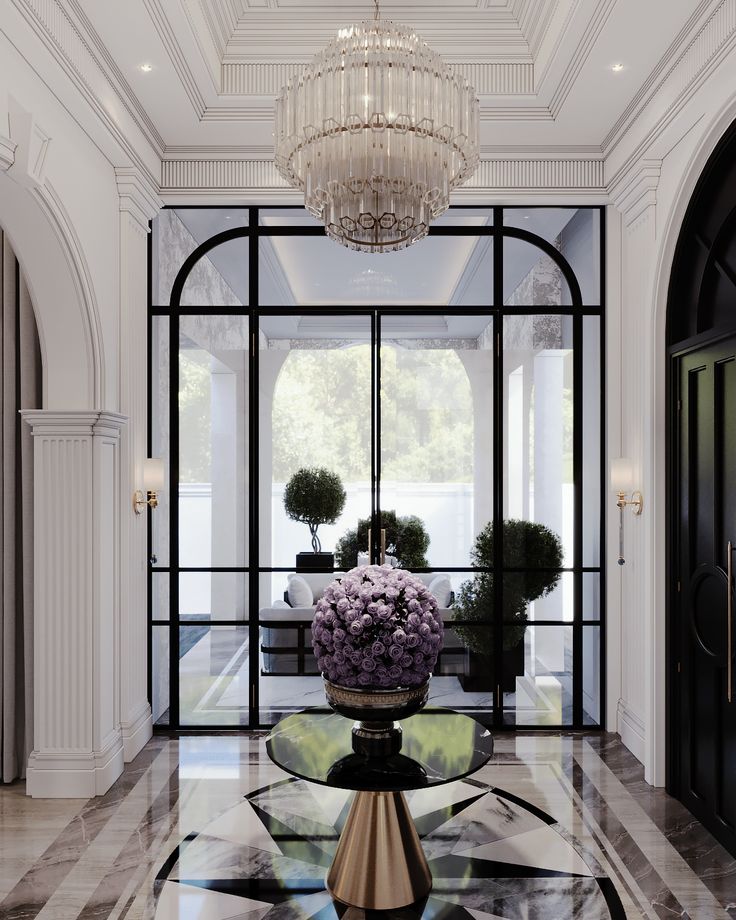 an elegant foyer with chandelier and flowers in vases on the side table