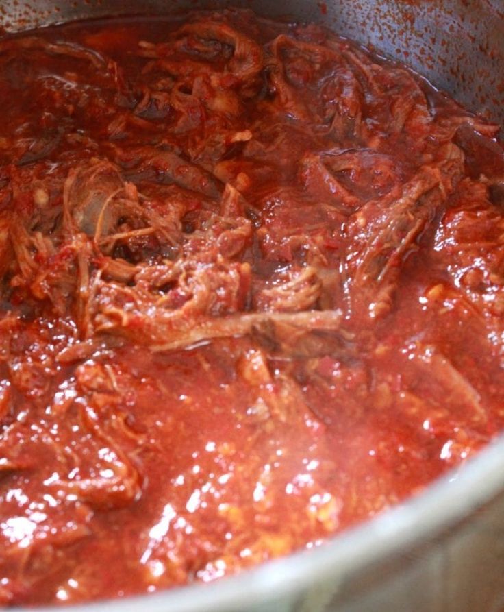 a pot filled with meat and sauce on top of a stove