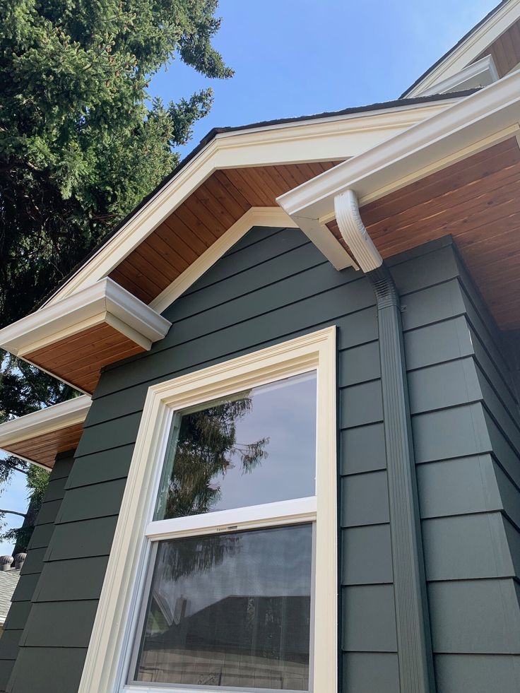 the corner of a house with an open window and wood shingles on it's side