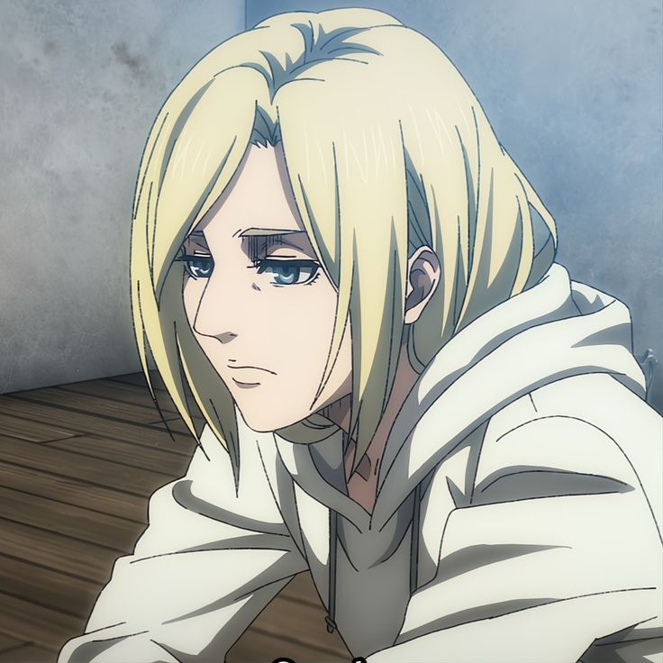 an anime character with long blonde hair and blue eyes sitting on the floor in front of a wall