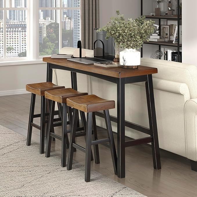 three stools sit at the end of a table in front of a couch and window