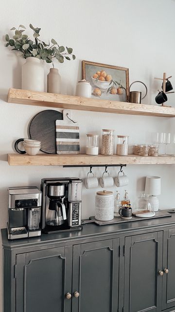 there is a coffee maker and some cups on top of the shelves in this kitchen