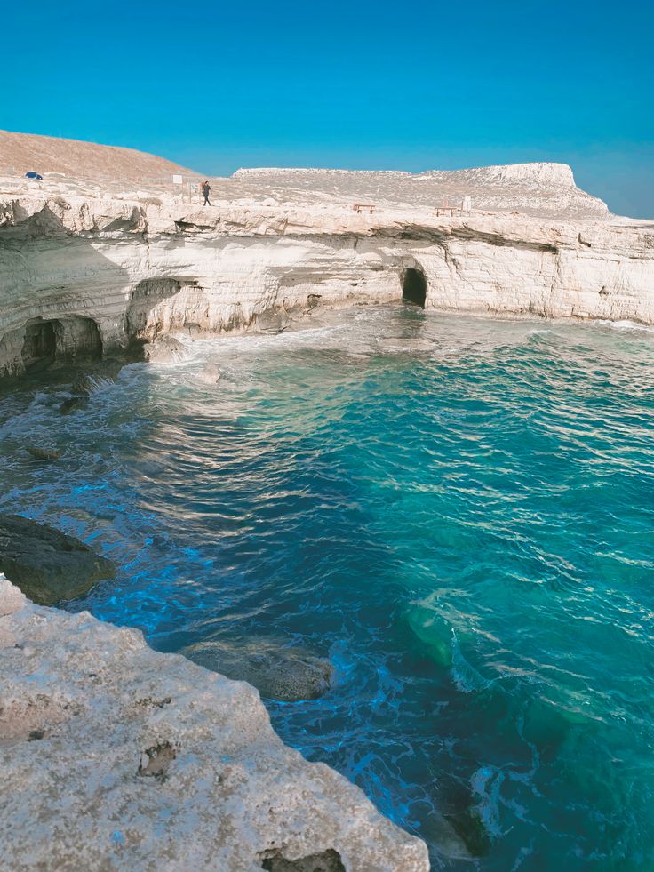 people are standing on the edge of an ocean cliff