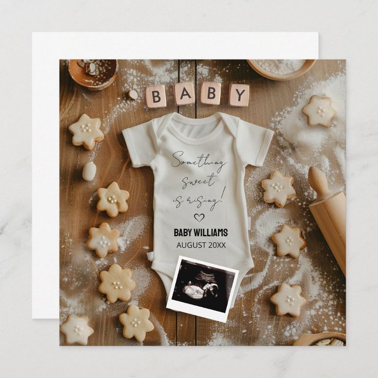 a baby announcement card with cookies and cookie cutters on the table next to it