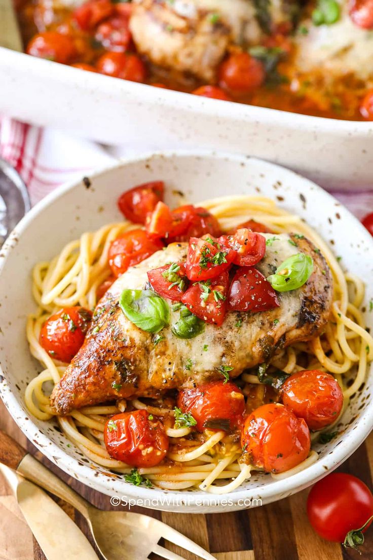 a white bowl filled with chicken, tomatoes and pasta