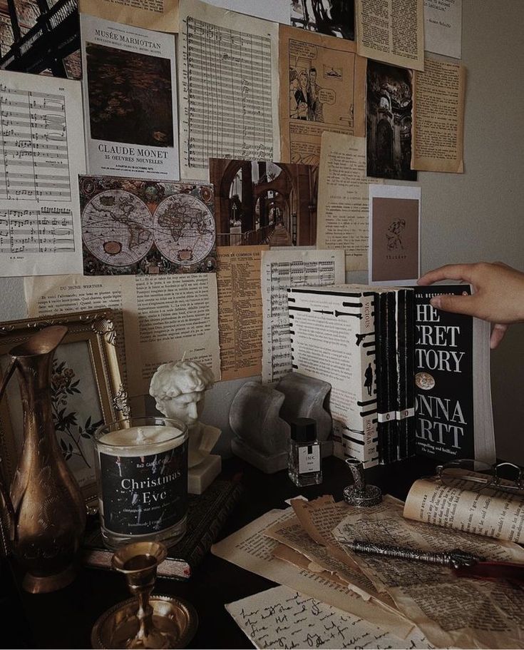 a table topped with lots of books next to a wall covered in old fashioned papers