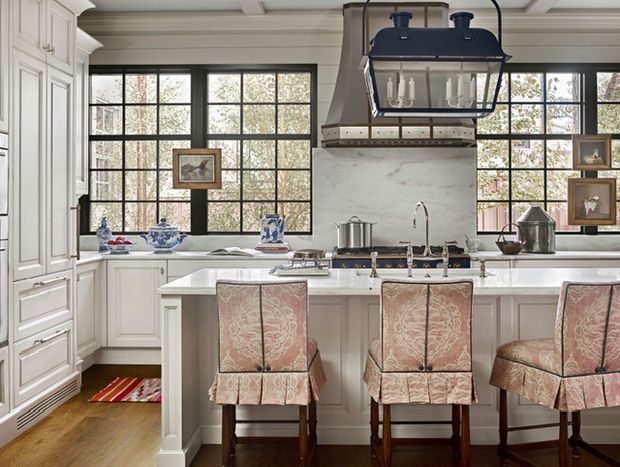 a kitchen with white cabinets and marble counter tops, along with four chairs in front of the island