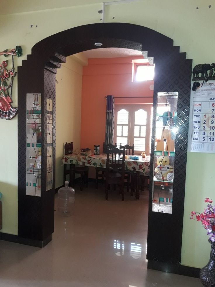 an archway leads into a dining room with tables and vases on the table in front of it