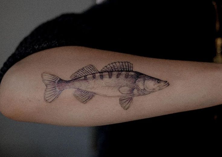 a woman's arm with a fish tattoo on it