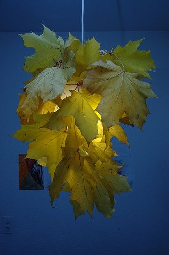 a light hanging from a ceiling with yellow leaves