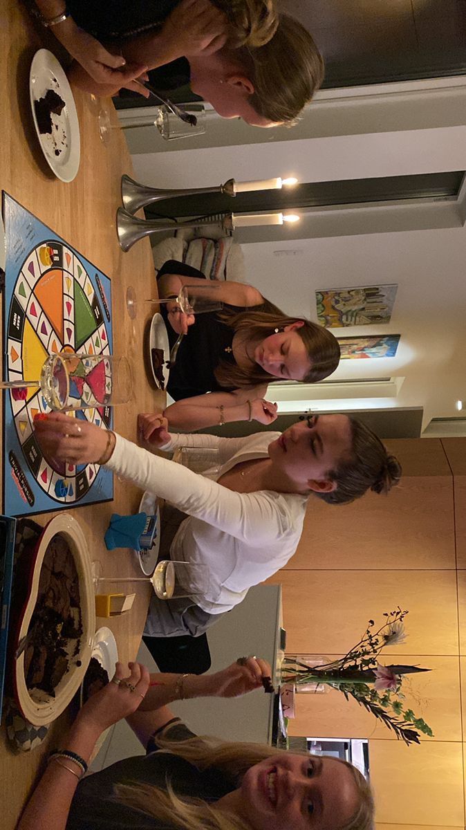 three women standing around a board game on the wall