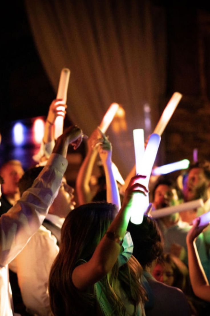 many people are holding up their cell phones in the air at an outdoor event with lights on them