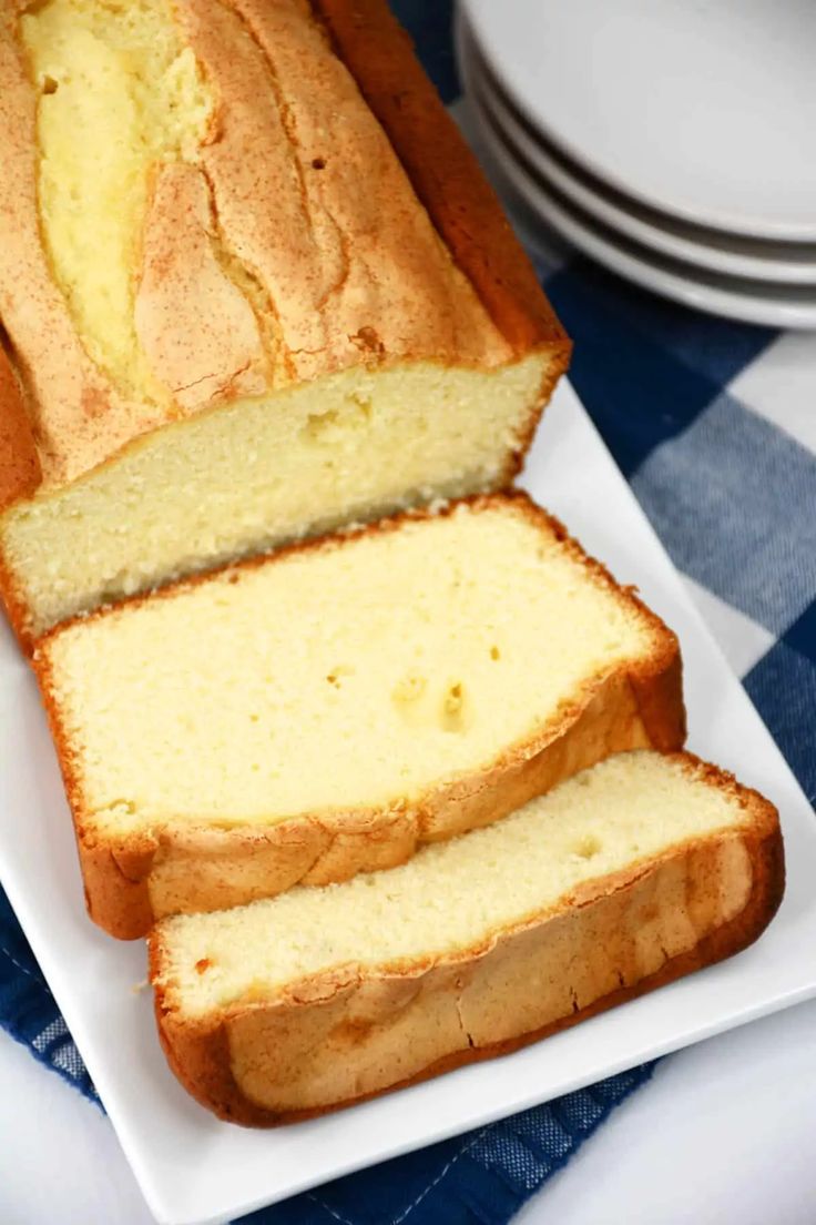 a loaf of lemon pound cake sitting on top of a white plate next to a blue and white checkered table cloth