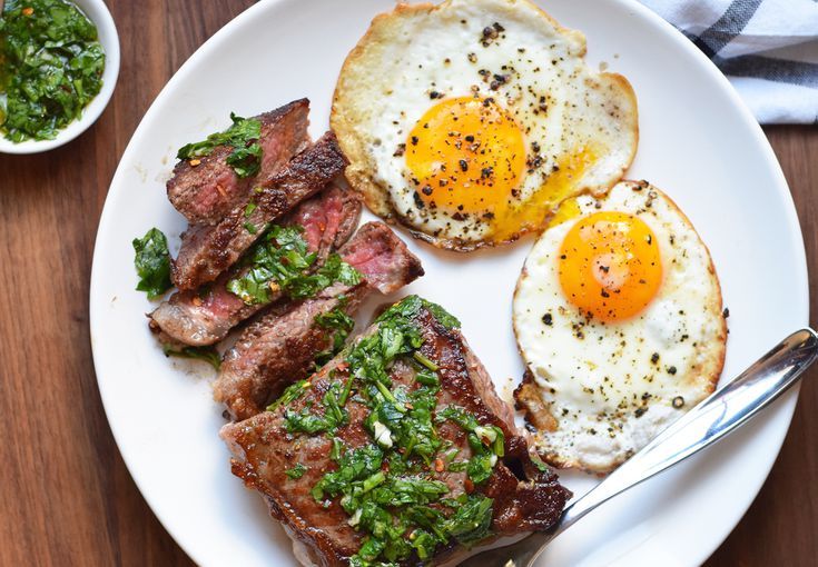 steak, eggs and bread on a white plate