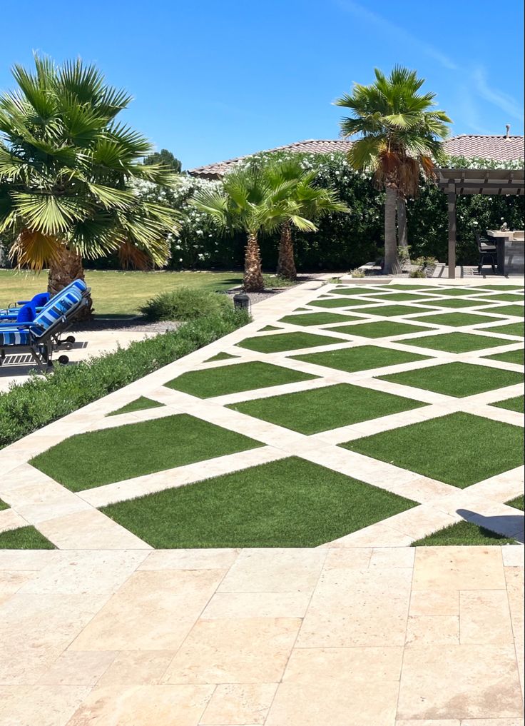 an outdoor area with artificial grass and palm trees in the background, surrounded by lawn furniture