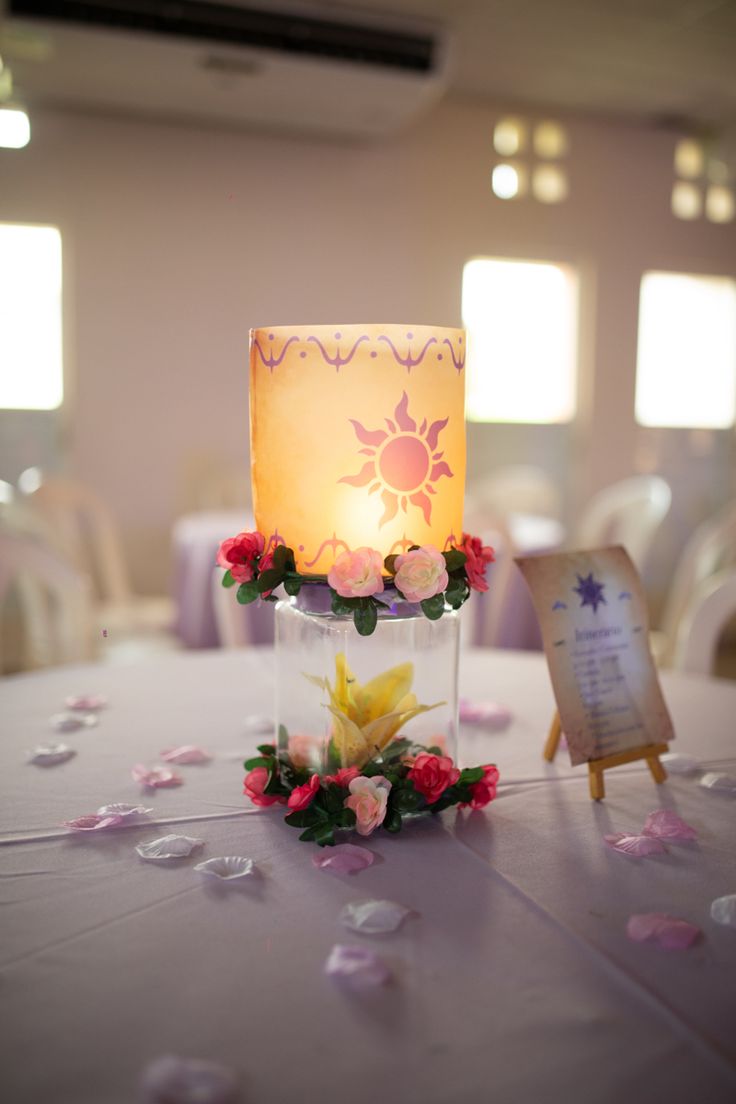 a lit candle on top of a table with flowers and confetti around it