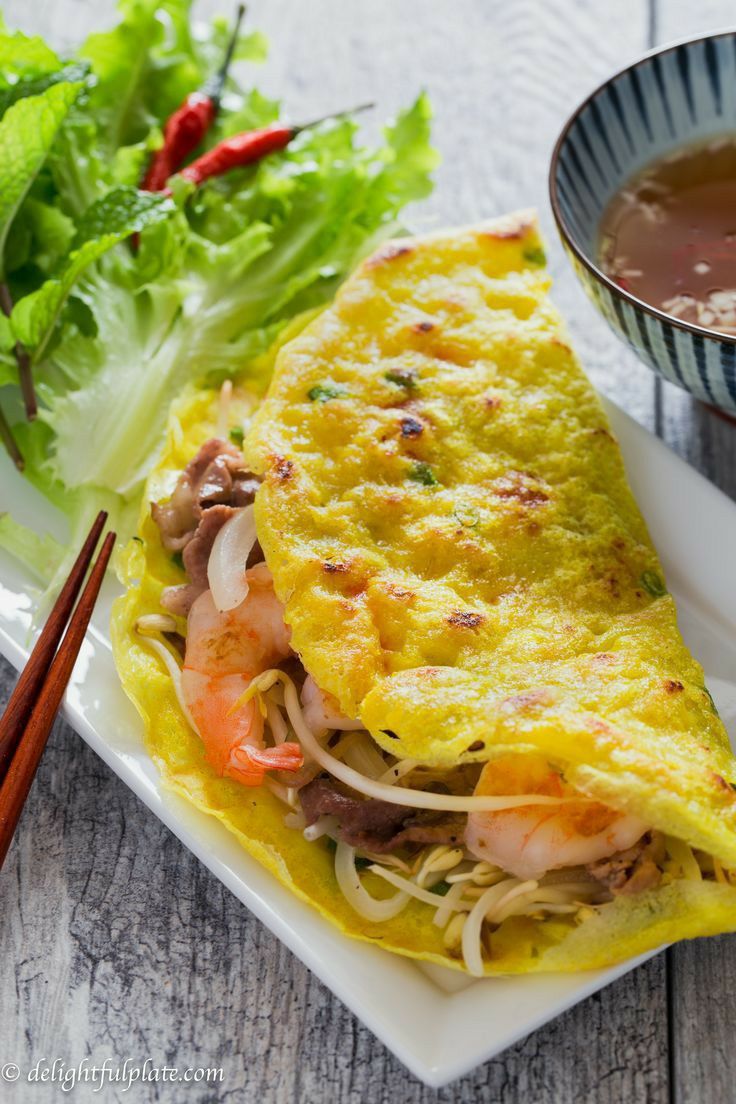 an omelet on a plate with chopsticks next to it and a bowl of soup