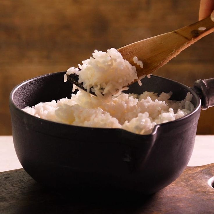 someone is scooping rice into a black bowl